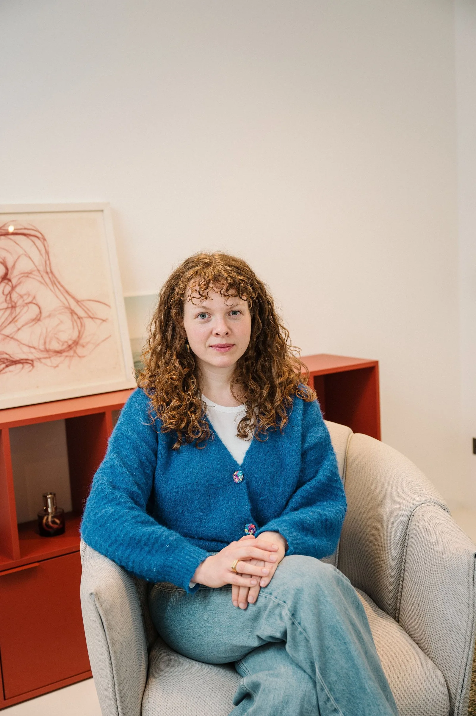 Kim Busch, Psychotherapeutin in Fachausbildung unter Lehrsupervision (Psychoanalytisch-Psychodynamische Therapie), sitzt im Sessel.