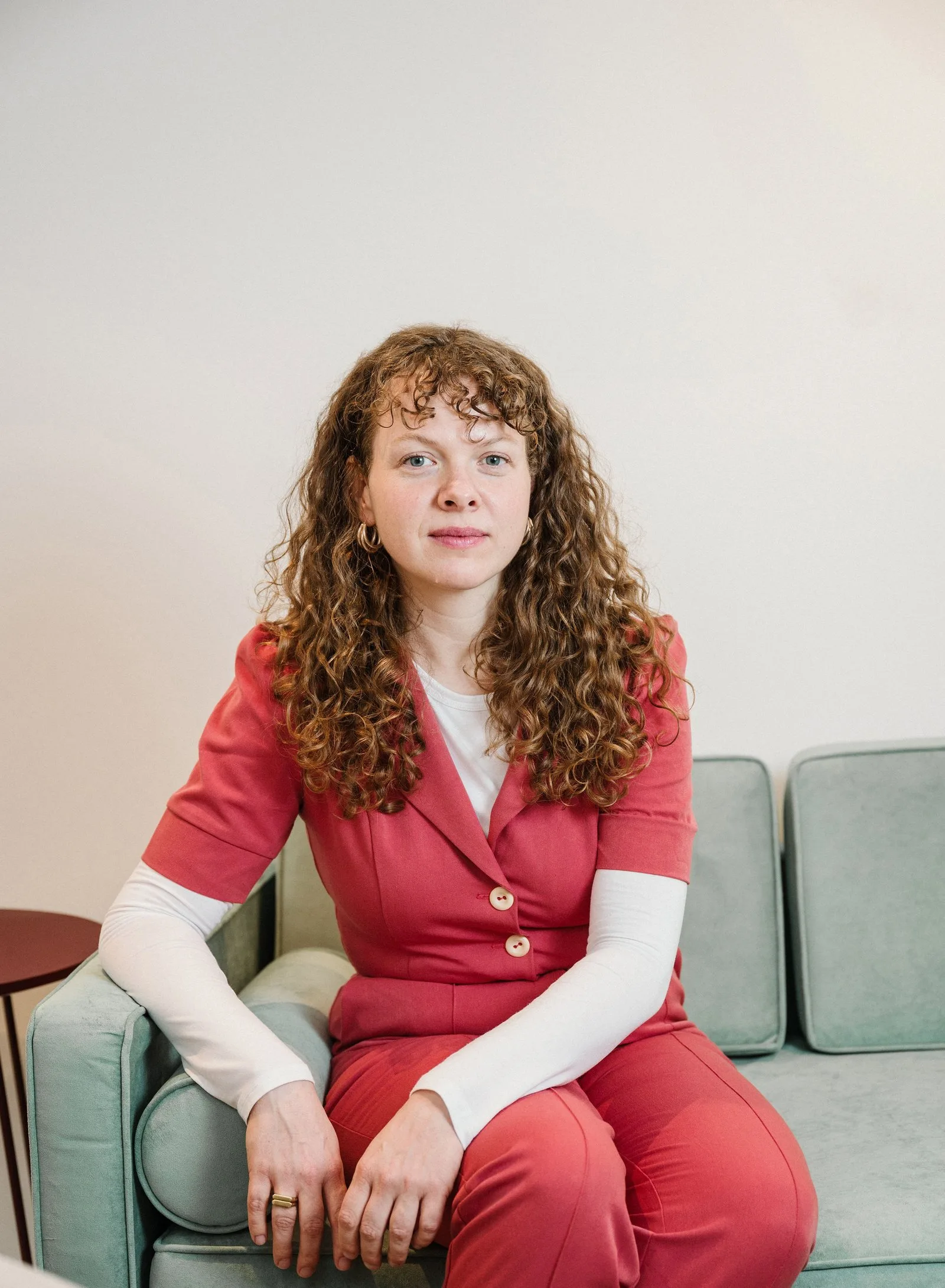 Kim Busch, Psychotherapeutin in Fachausbildung unter Lehrsupervision (Psychoanalytisch-Psychodynamische Therapie), sitzt auf einem Sofa.